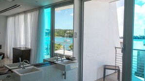 Ein modernes Badezimmer mit zwei Waschbecken, einem Spiegel und Meerblick durch ein großes Fenster.