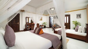 A bedroom with a large bed, a smaller bed, a desk, and a chair. There is a door and a window. - Bronam Residence & Spa (Siem Reap)