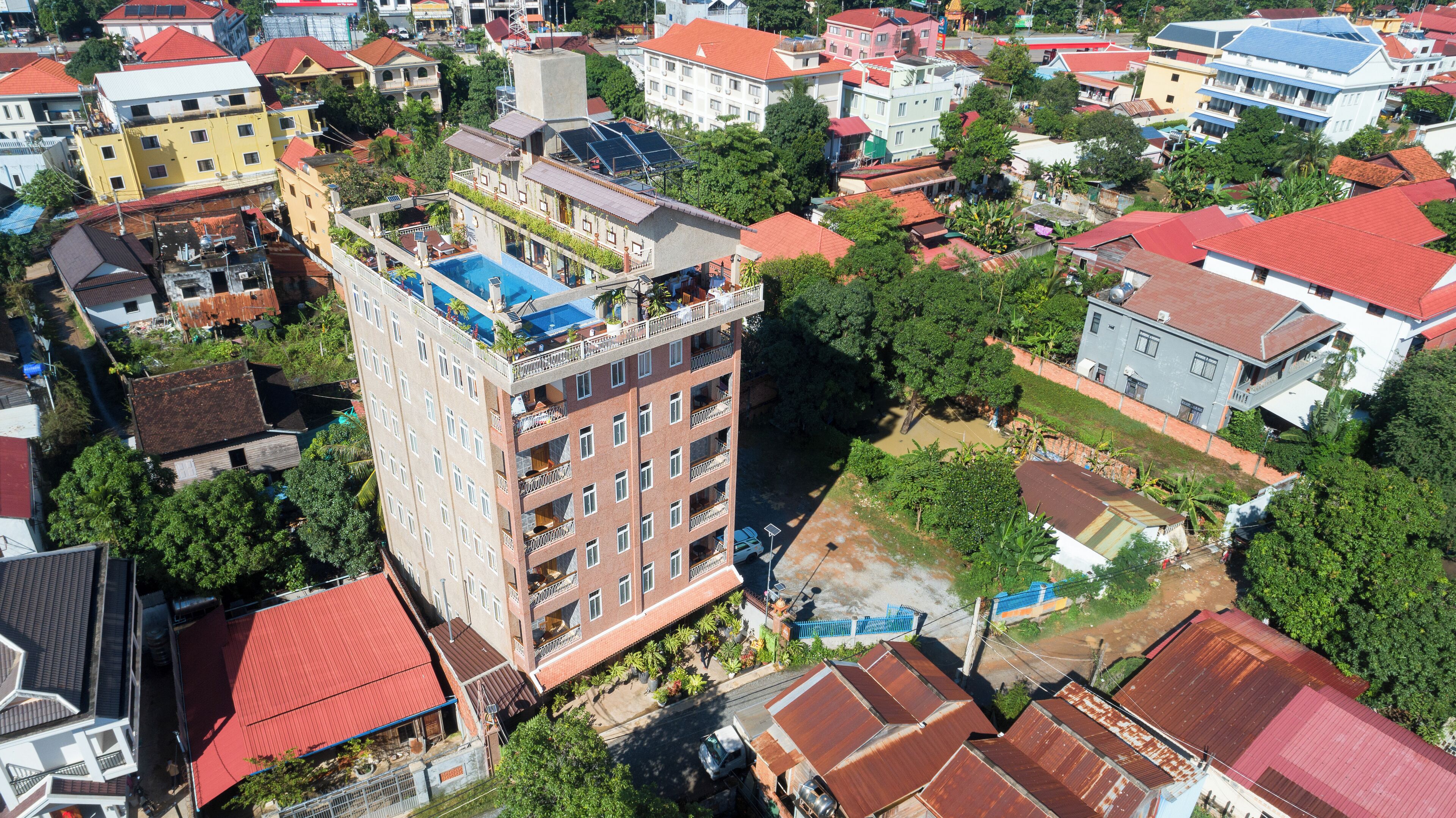 A multi-story building with balconies, a swimming pool, and solar panels.