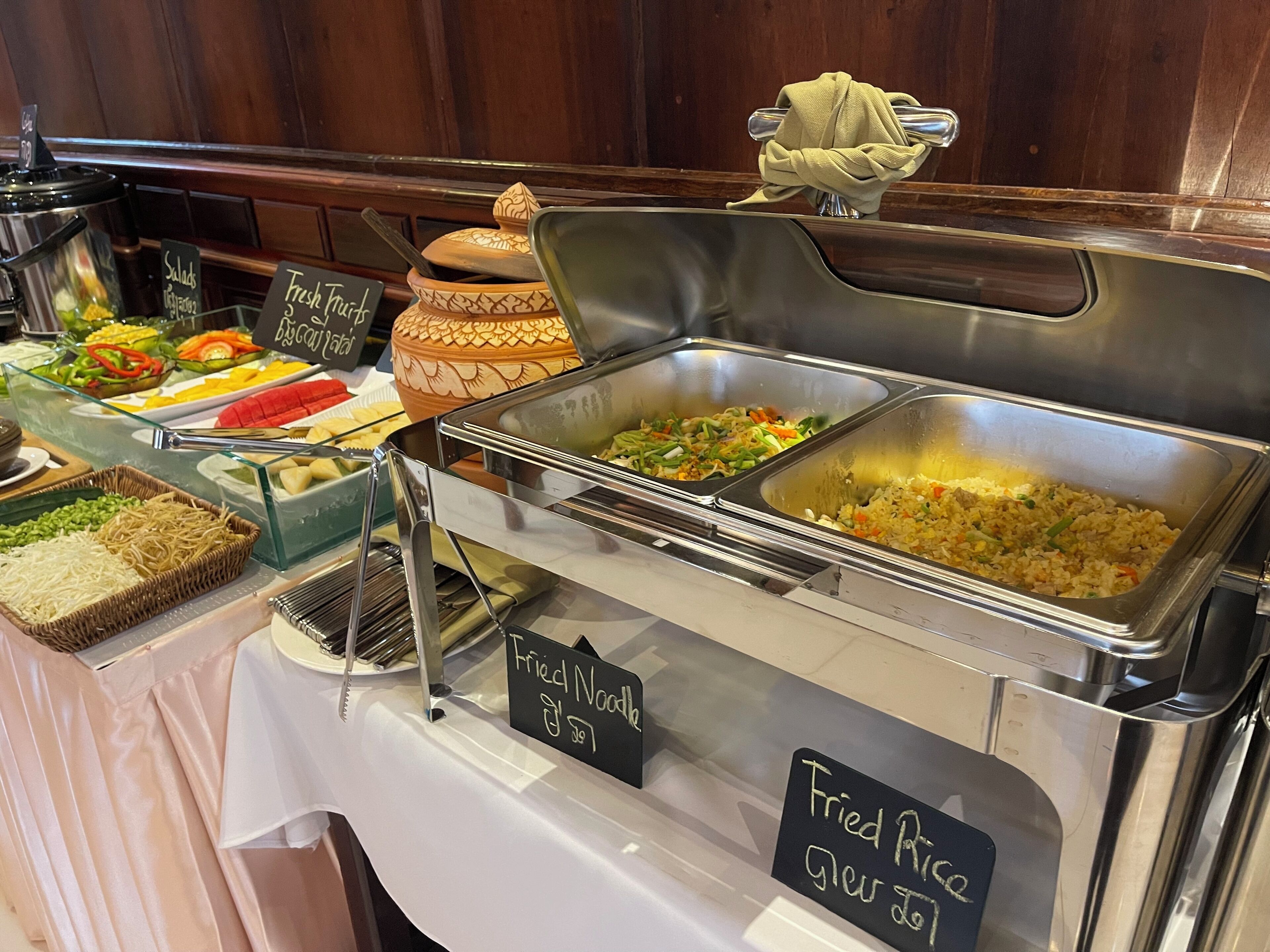Un buffet proposant une variété de plats, notamment des salades, des fruits frais et du riz frit.