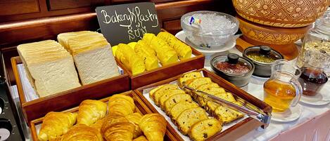 Mostrador de panadería con diversos pasteles y pan.