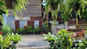 A garden with potted plants, a wooden fence, and a pathway leading to a building. - Bronam Residence & Spa (Siem Reap)