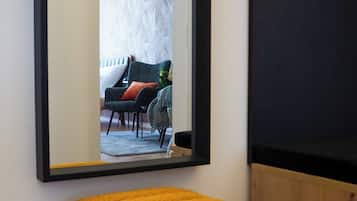 A room with a large mirror reflecting a living area with a sofa, chairs, and a table.