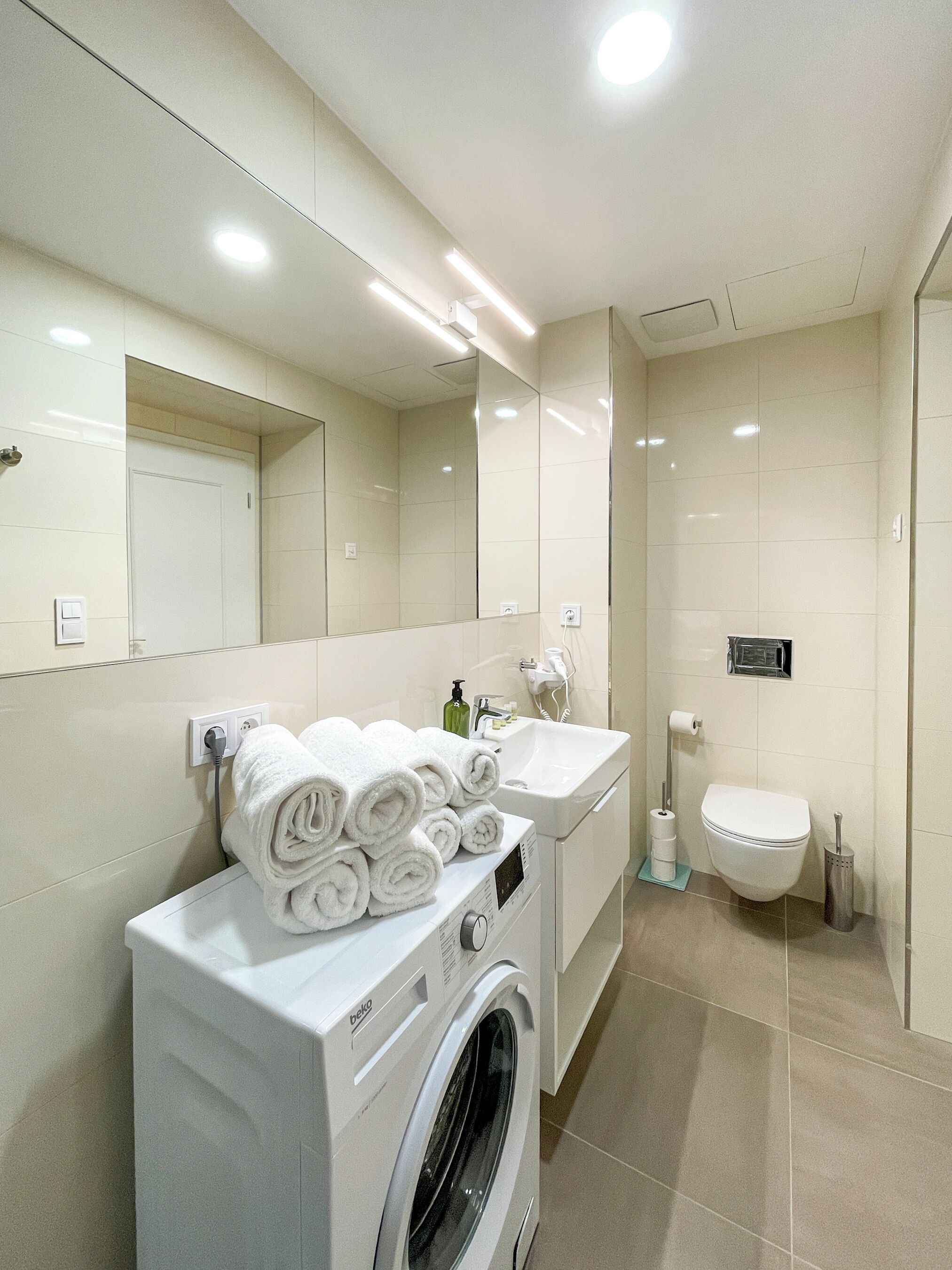 Un baño moderno con lavadora, lavamanos y retrete.