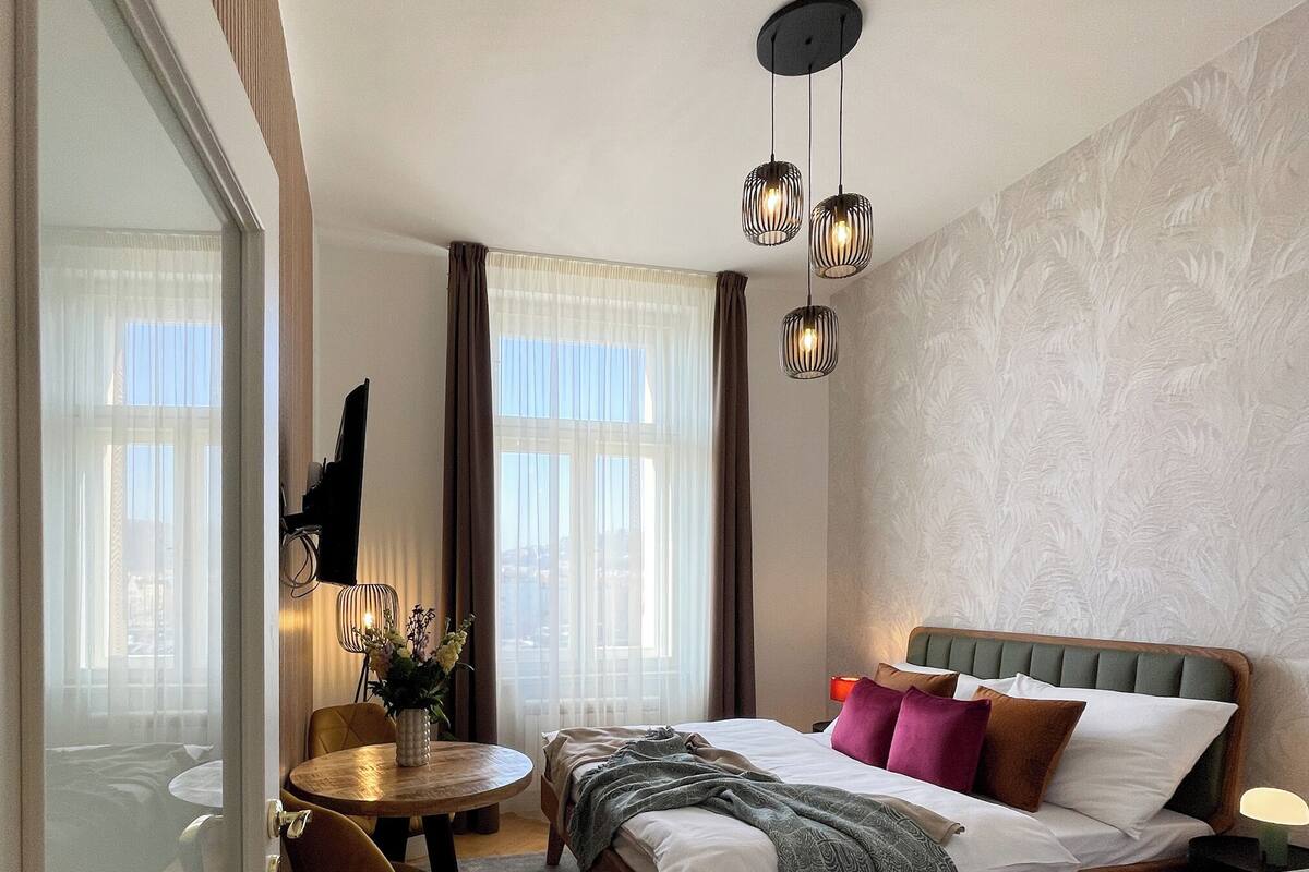A modern bedroom with a bed, bedside table, and a desk with a chair.