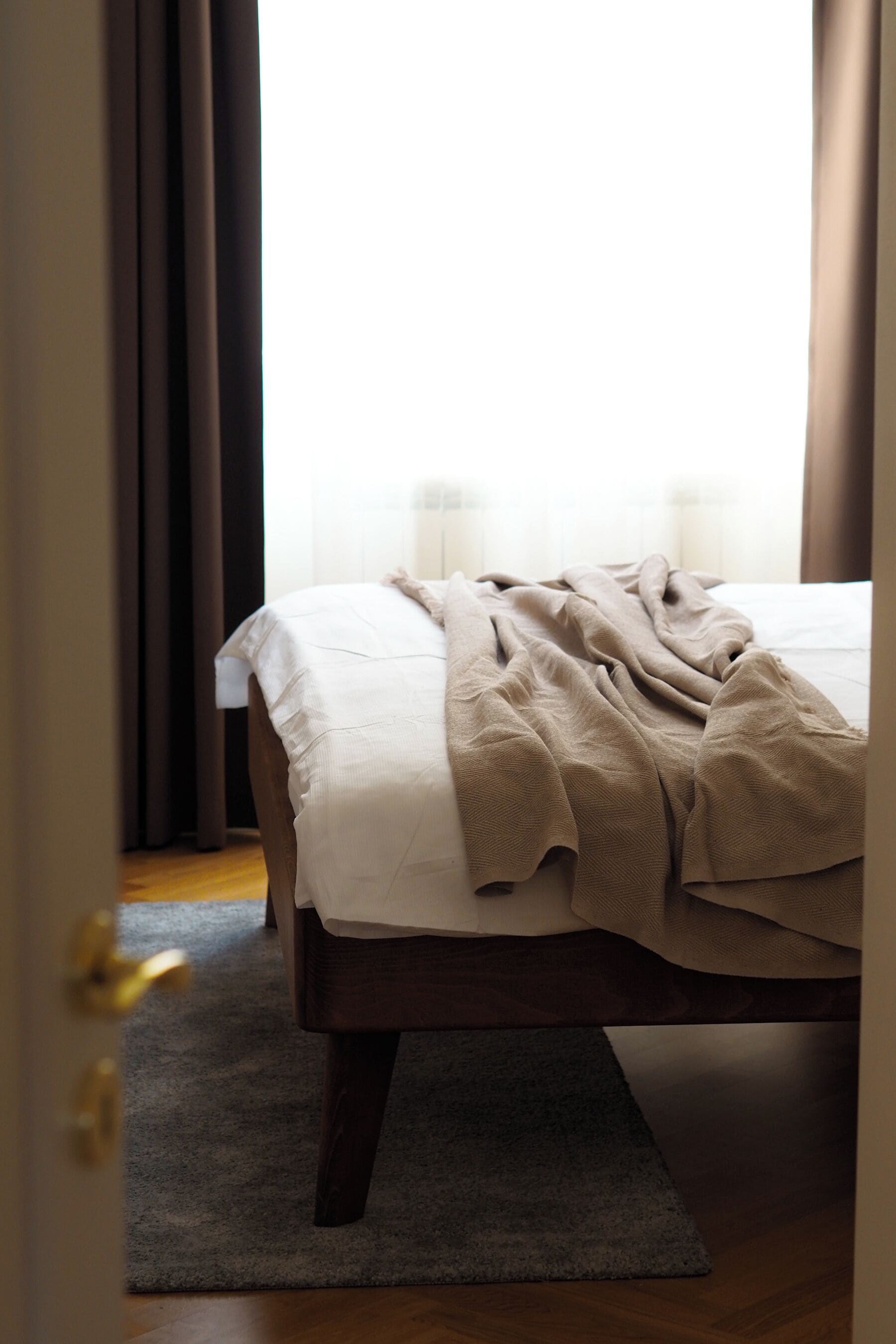 A bedroom with a bed, a rug, and curtains.