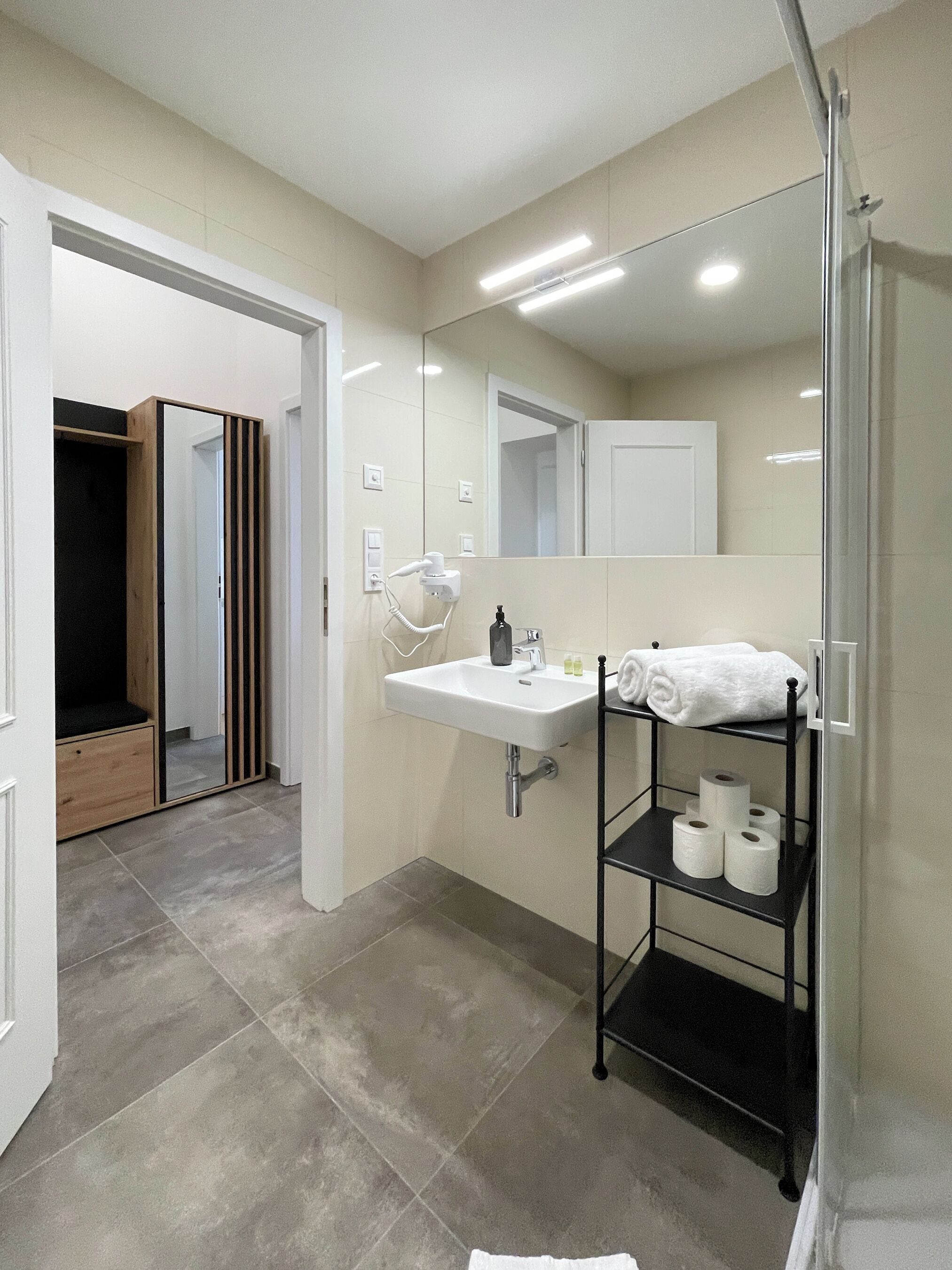 A modern bathroom with a large mirror, a sink, and a towel rack.