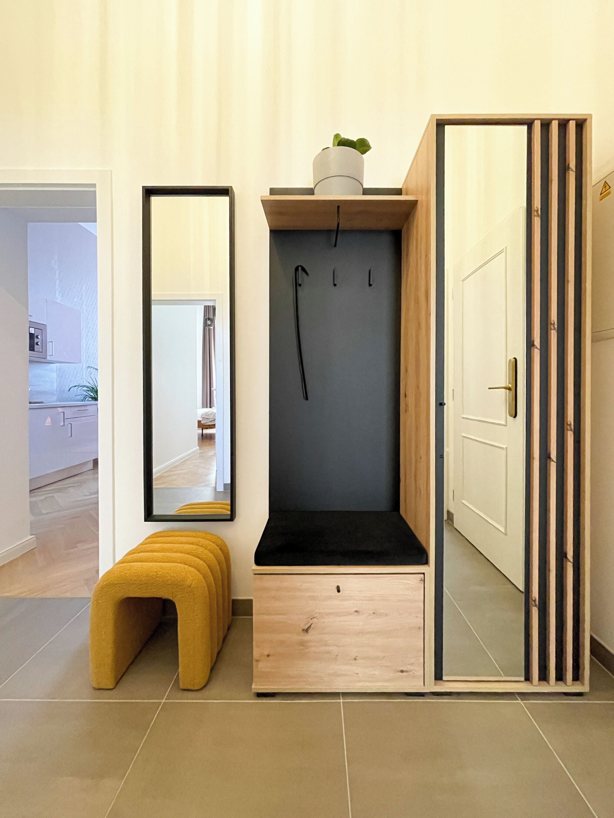 A modern bathroom with a wooden bench, a mirror, and a towel rack.