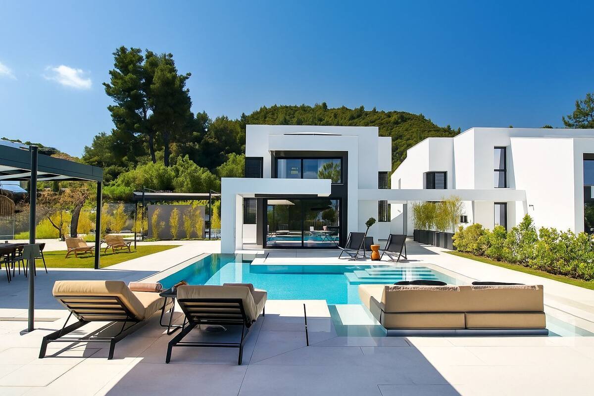 Une maison moderne dotée d’une piscine, d’un espace salon extérieur et d’un patio couvert.