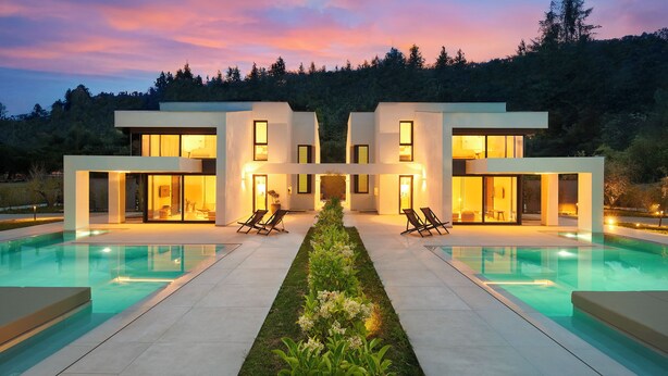 A modern house with a swimming pool, two lounge chairs, and a well-lit entrance. - Seasalt Luxury Villas (Pefkochori)