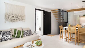 A modern living room with a sofa, coffee table, and dining area. - Seasalt Luxury Villas (Pefkochori)