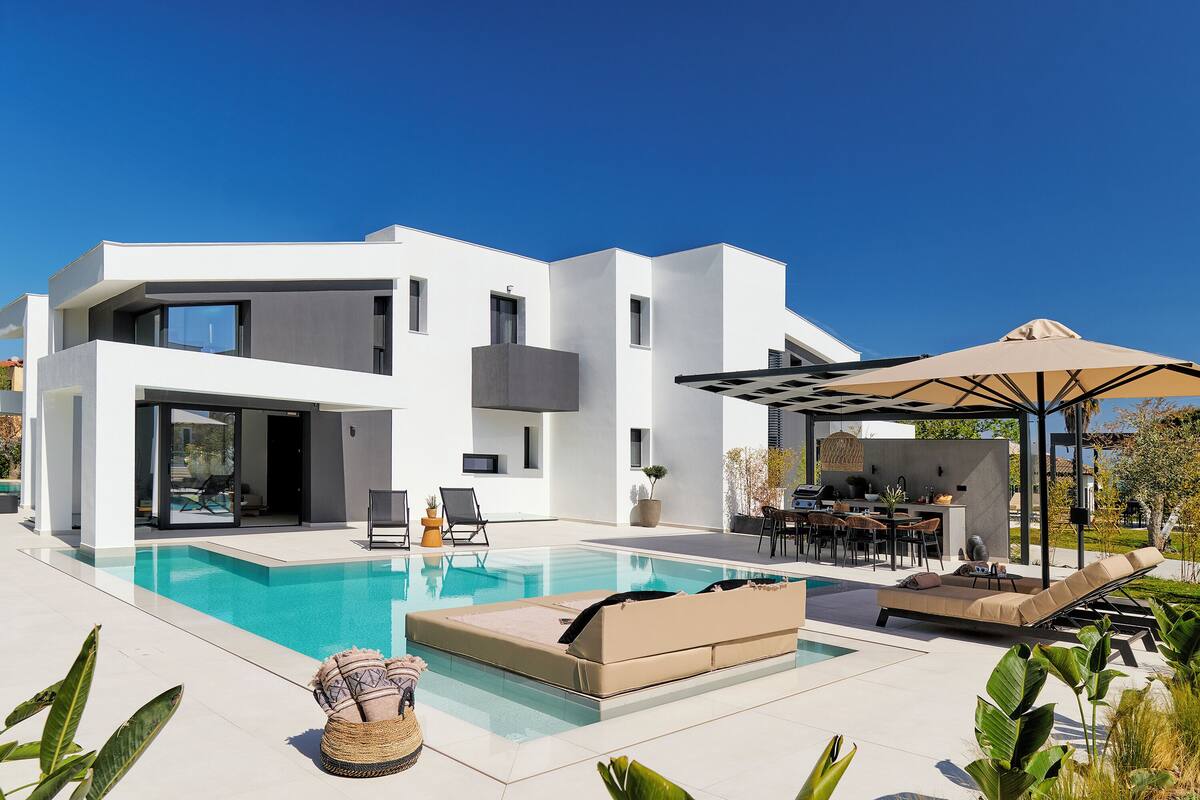 Une maison moderne dotée d’une piscine, de mobilier d’extérieur et d’un patio couvert.