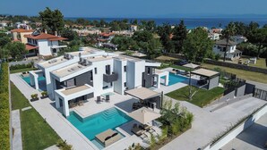 A modern house with a swimming pool, multiple balconies, and a view of the sea. - Seasalt Luxury Villas (Pefkochori)