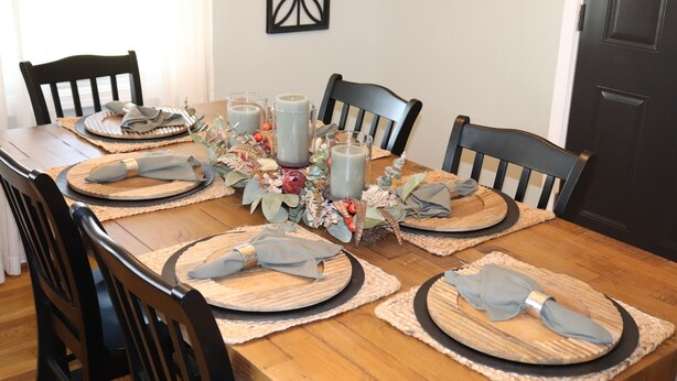 A dining table set with placemats, napkins, and a centerpiece.