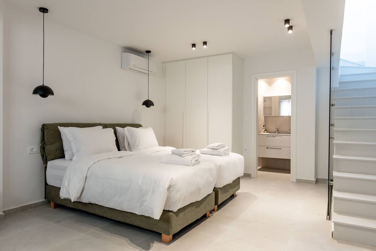Ein modernes Schlafzimmer mit einem Bett, Nachttischen und einem begehbaren Kleiderschrank.