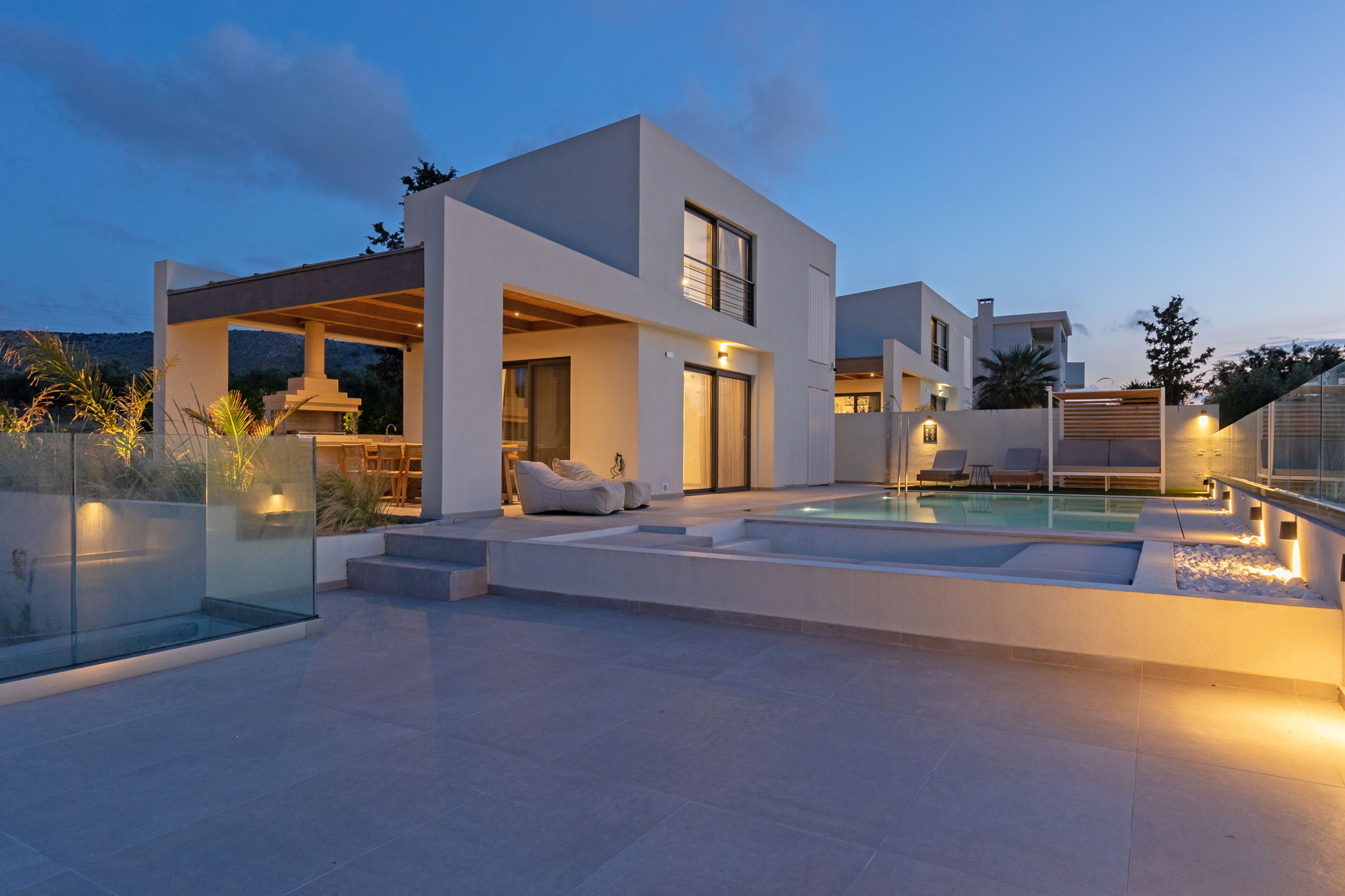A modern house with a swimming pool, outdoor seating, and a covered patio area.