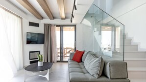 A modern living room with a grey sofa, a black coffee table, and a flat-screen TV.