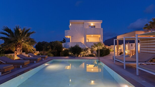 A modern pool area with lounge chairs and a building in the background.