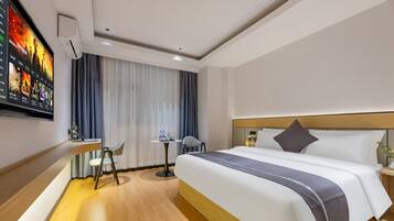 A hotel room with a large bed, a desk, and a TV mounted on the wall.