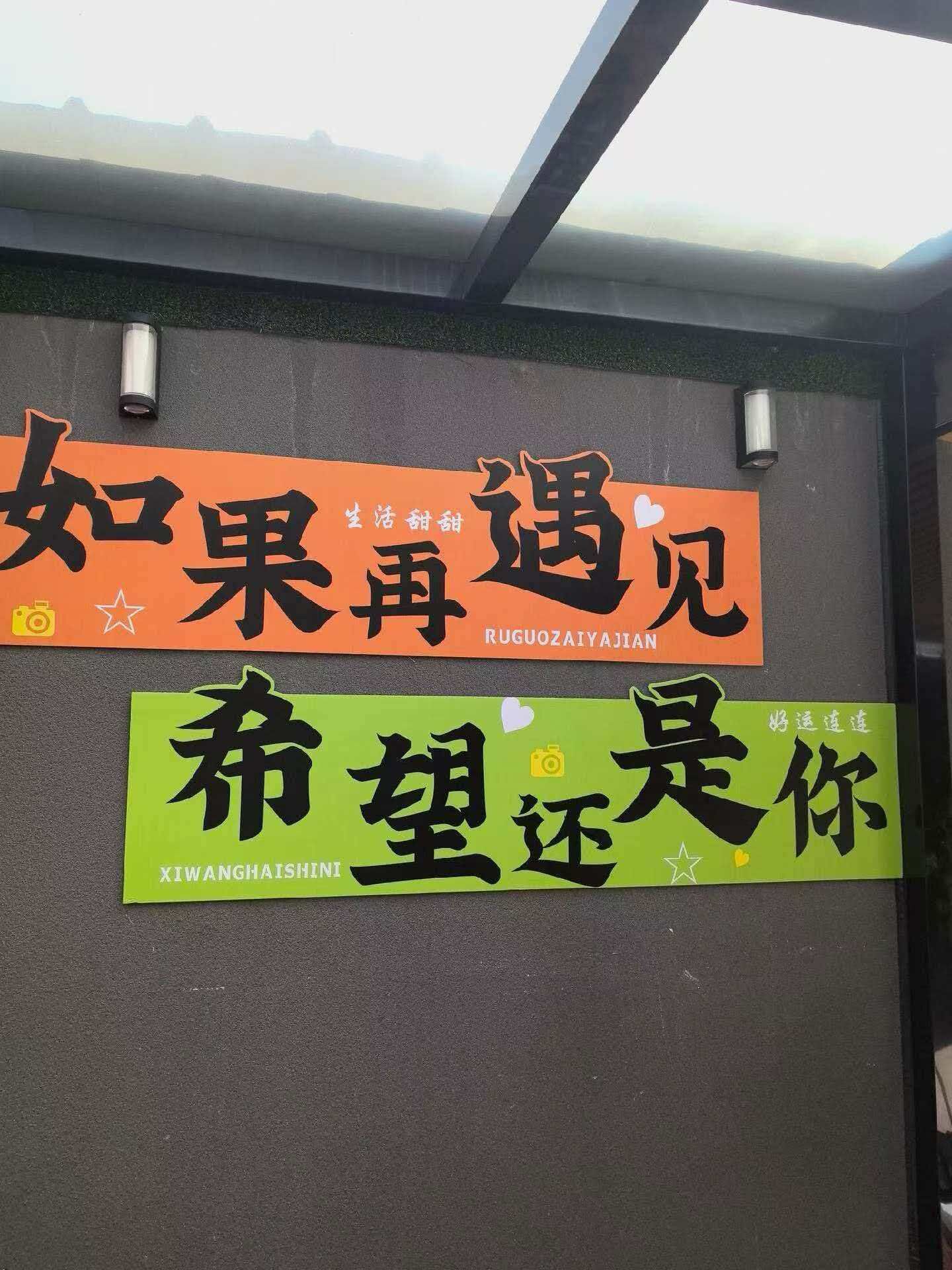 Two signs with Chinese characters, one orange and one green, mounted on a wall.
