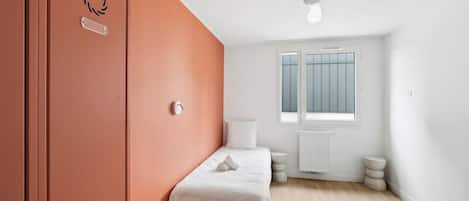 A bedroom with a bed, a ceiling fan, a window, and a radiator.
