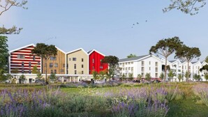 Een rij moderne gebouwen met een mix van bouwstijlen, waaronder een rood gebouw met een schuin dak en een beige gebouw met een plat dak.