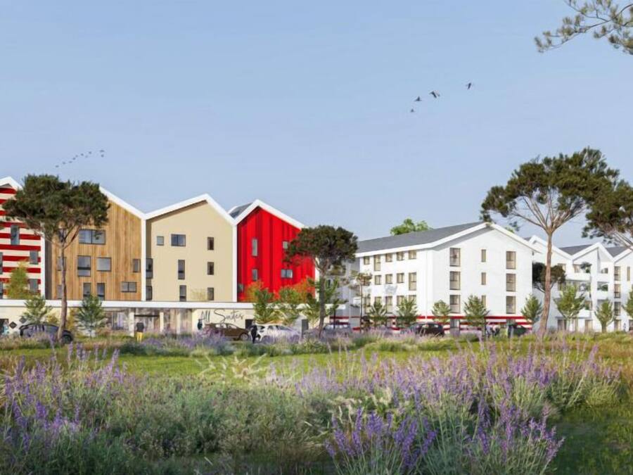 Una hilera de edificios modernos con una variedad de estilos arquitectónicos, incluyendo un edificio rojo con techo inclinado y uno beige con techo plano.