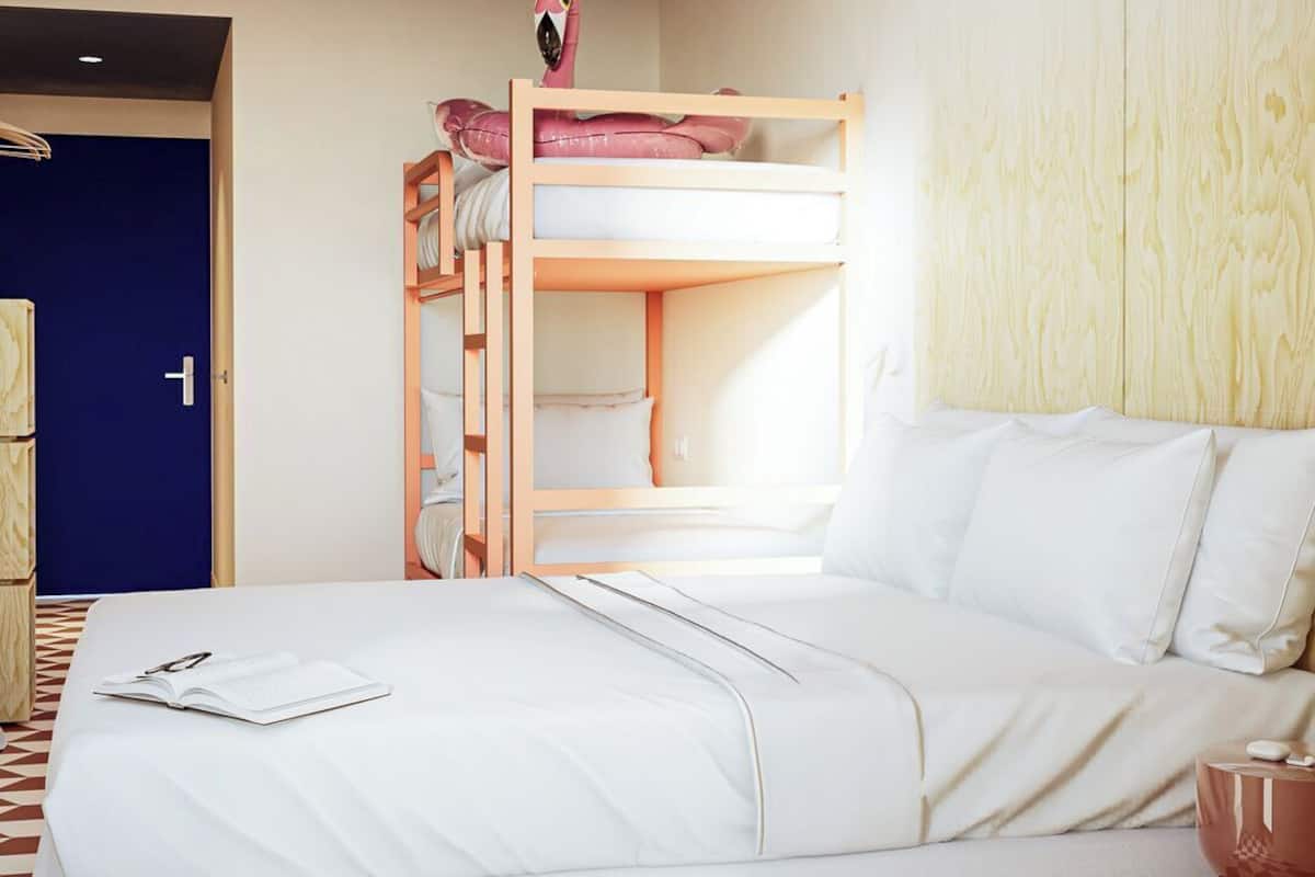 Een slaapkamer met een stapelbed, een bureau met stoel en een nachtkastje met lamp.