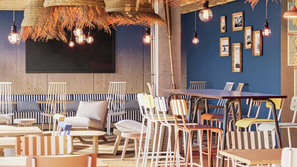 Een restaurant met gestreepte stoelen, hangende geweven lampen en ingelijste foto’s aan de muur.