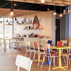 Ein modernes Café mit Holzmöbeln, hängenden Pendelleuchten und verschiedenen Sitzgelegenheiten.