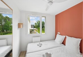 Un dormitorio con dos camas, una ventana, ventilador de techo y vistas al exterior.