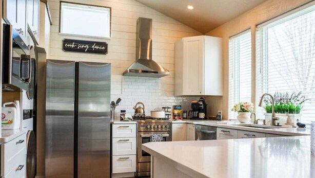 A modern kitchen with stainless steel appliances, a central island, and a view of the outdoors. - No Fee | New Private Cottage | Fireplace + Full Kitchen (Post Falls)