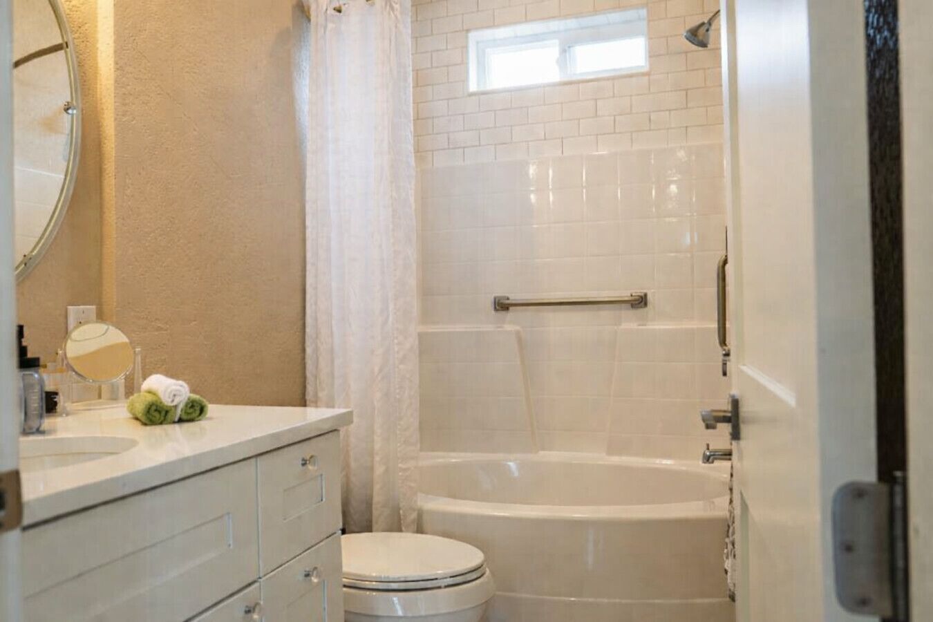 Un baño con inodoro, bañera, ducha, lavamanos con espejo y un perchero para toallas.