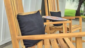 A wooden chair with a black cushion and a small round table with a colorful pattern. - No Fee | New Private Cottage | Fireplace + Full Kitchen (Post Falls)