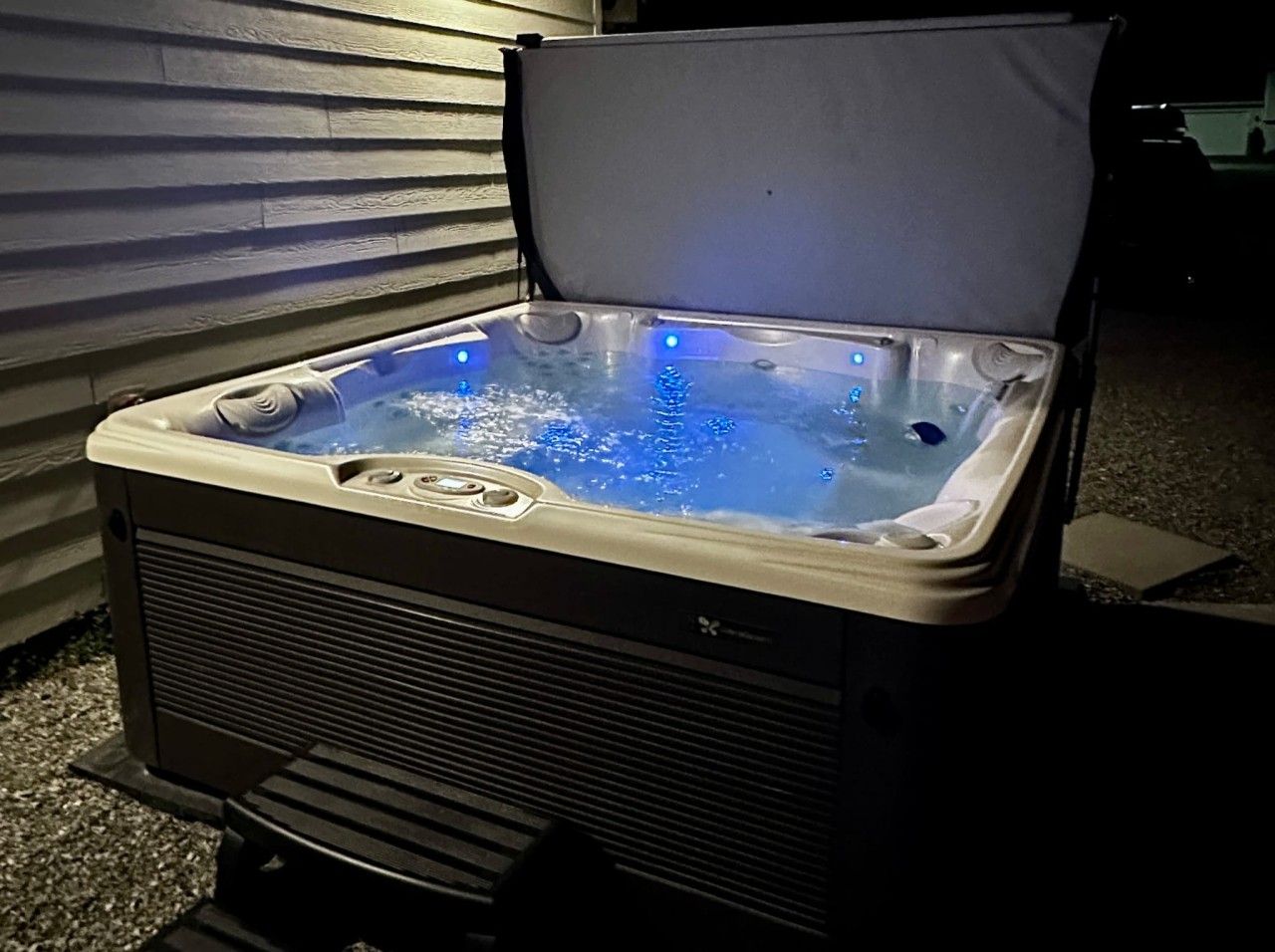A hot tub with a cover, a control panel, and a water pump.
