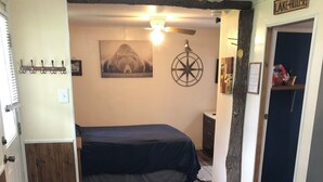 Una habitación acogedora con una cama, un banco y una puerta que indica "LAKE-HOUSE".