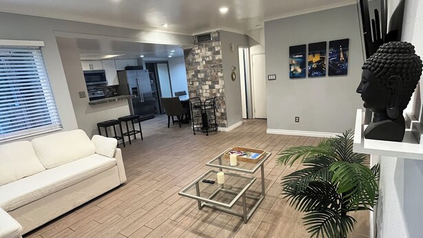 A modern living room with a white sofa, a glass coffee table, and a potted plant. - Spacious & Accessible 2-bedroom Condo with Pool & Private Garage, BEST LOCATION! (Las Vegas)