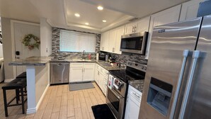 A modern kitchen with white cabinets, a stainless steel refrigerator, a microwave, an oven, and a dishwasher. - Spacious & Accessible 2-bedroom Condo with Pool & Private Garage, BEST LOCATION! (Las Vegas)
