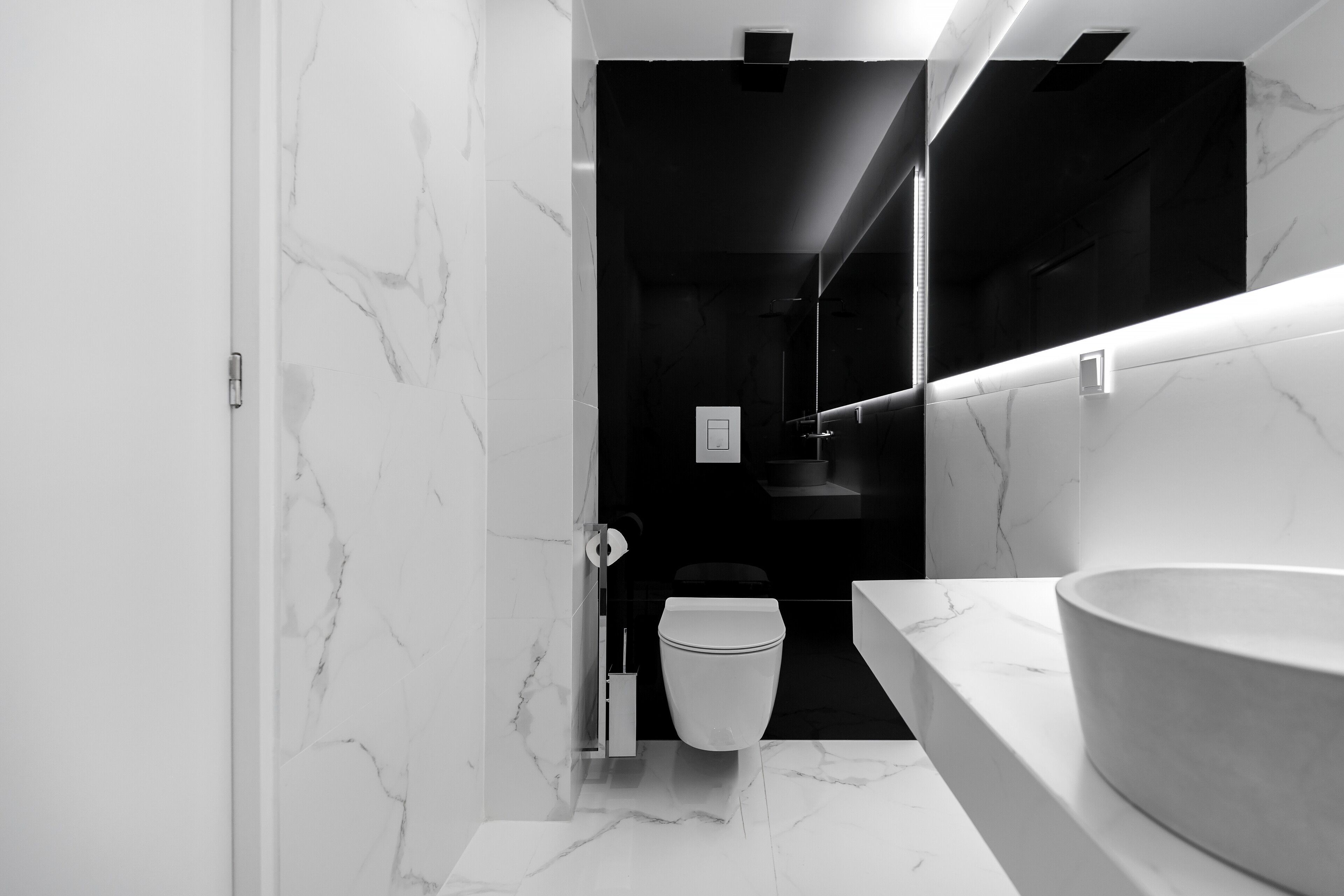 A modern bathroom with a marble floor, a white sink, and a toilet.