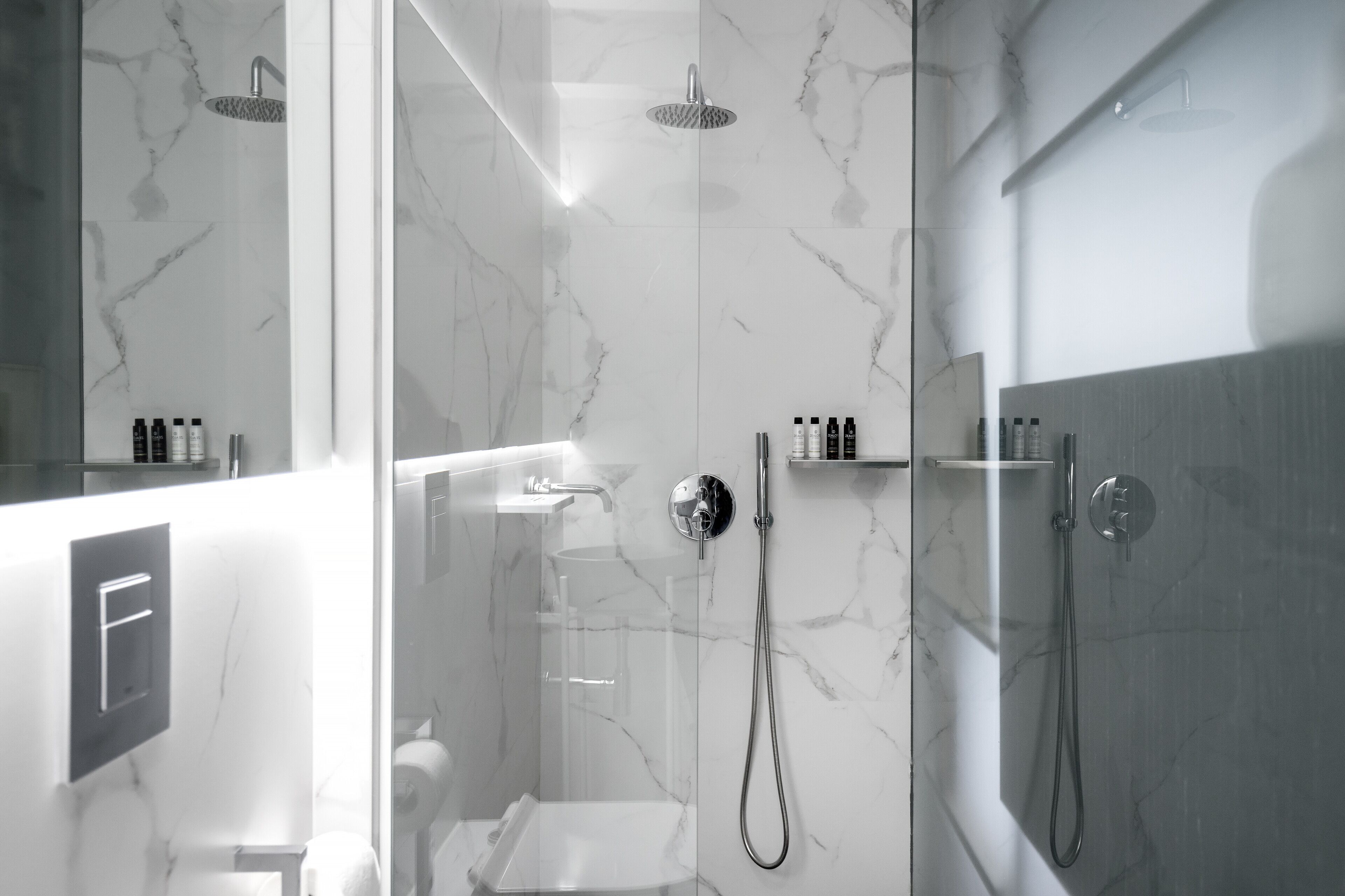A modern bathroom with a glass-enclosed shower, marble walls, and a minimalist design.