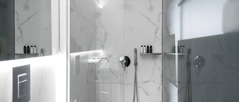 A modern bathroom with a glass-enclosed shower, marble walls, and a minimalist design.