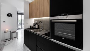 A modern kitchen with black and wooden cabinets, a built-in oven, and a stainless steel sink. - Elysan Urban Stays (Athens)