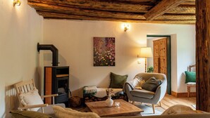 Un salon chaleureux avec une cheminée, un canapé, un fauteuil et un tableau accroché au mur.