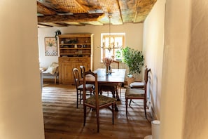 Un comedor con una mesa y sillas de madera, una araña y una estantería.