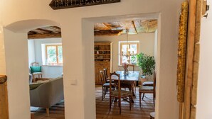 Un espace repas avec des meubles en bois, un lustre et une vue sur une autre pièce, accessible par une arche.
