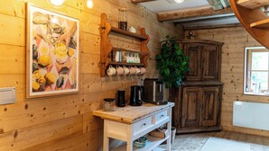 Un intérieur en bois comprenant un comptoir de cuisine, des étagères avec des tasses, une machine à café et un placard.