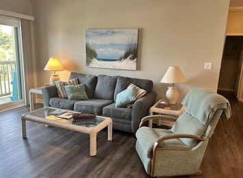 Spacious living with room with a deck over looking the pool side.