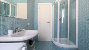 A bathroom with a white sink, a mirror, a shower with a glass door, and blue-tiled walls. -  Italianway Comfort - Braida 3 Orti  (Milan)
