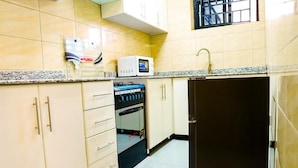 A kitchen with beige cabinets, a microwave, an oven, and a sink.