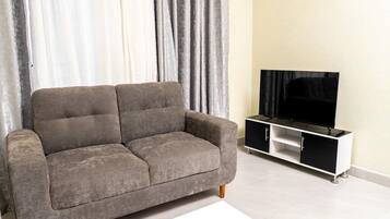 Un sofá gris con un televisor sobre un mueble blanco y negro en una sala de estar.